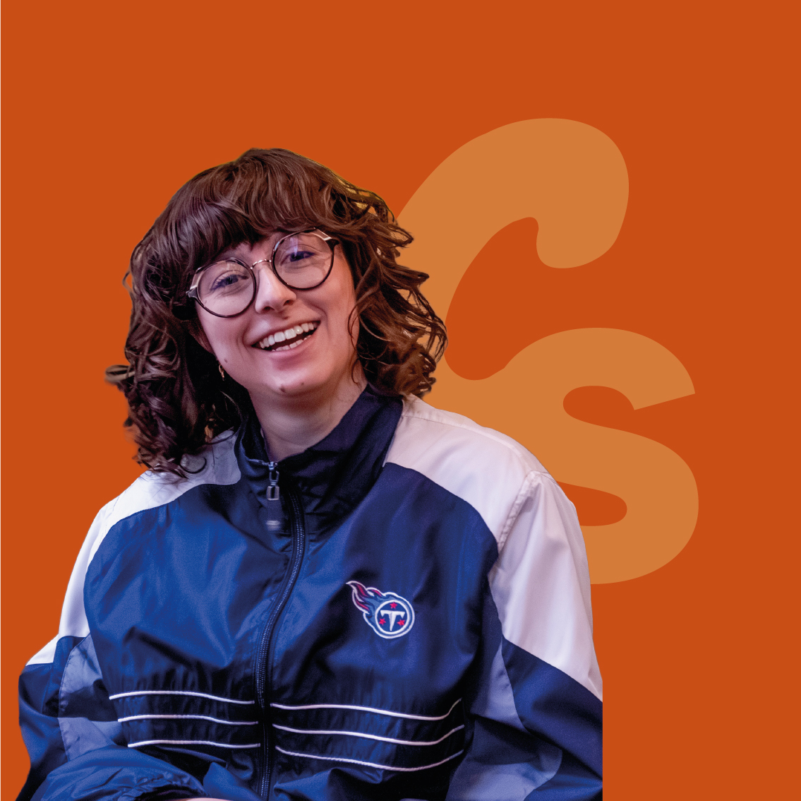 Femme blanche aux cheveux bouclés qui arrive aux épaules. Elle porte une veste de sport bleu et blanche. C'est votre photographe professionnelle à Grenoble.
